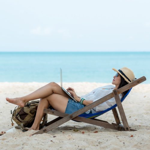 Lifestyle freelance woman using laptop working and relax on the beach.Â  Asian people on trampoline success and together your work pastime and meeting conference on internet in holiday.