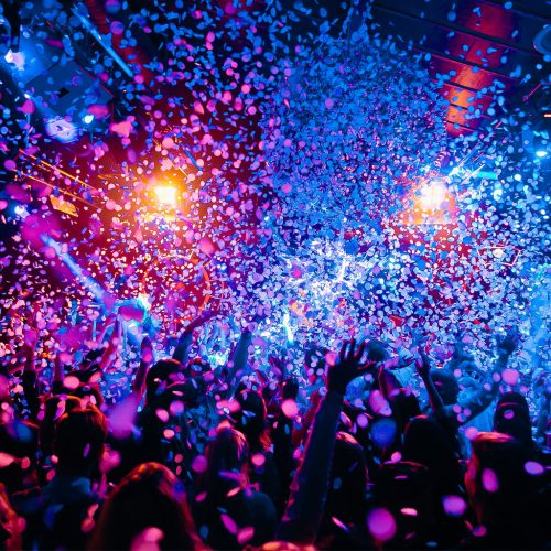 silhouettes of concert crowd in front of bright stage lights and confeti