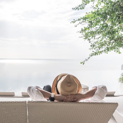 Relaxation holiday vacation of businessman take it easy happily resting on beach chair at swimming pool poolside beachfront resort hotel peacefully with sea or ocean view and summer sunny sky outdoor